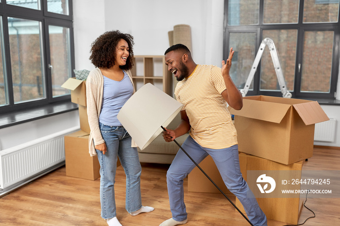 moving, people, repair and real estate concept - happy african american couple with lamp packing stu