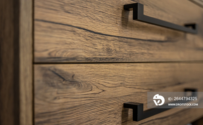 Close-up of modern dark wood furniture with black handles.