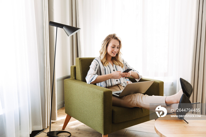 Beautiful young blonde woman sitting in armchair