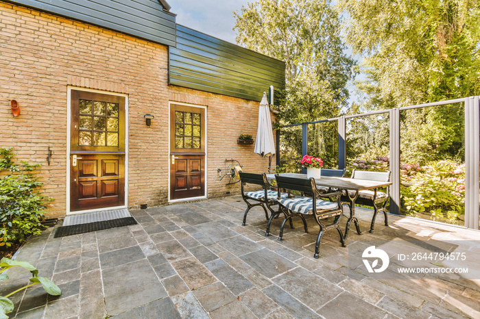 Neat paved patio with sitting area and small garden near wooden fence