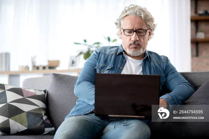 Serious elderly male typing on notebook computer