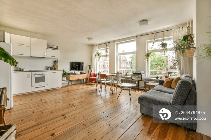 Table with chairs located near lounge area and kitchen in spacious room of contemporary apartment