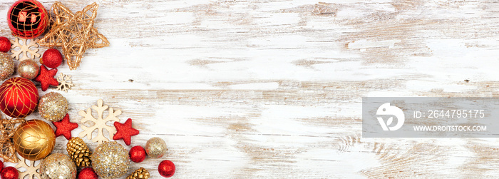 Christmas corner border of red and gold ornaments. Above view on a white rustic white wood banner ba