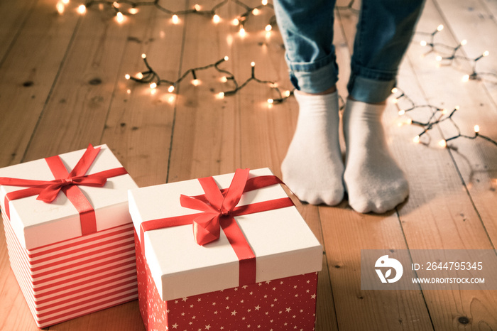 red gift boxes  feet and christmas lights on wooden floor