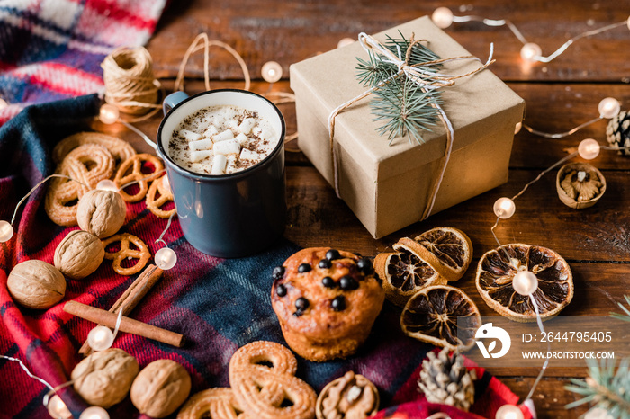 Giftbox surrounded by drink, cinnamon sticks, walnuts, lemon slices and cookies