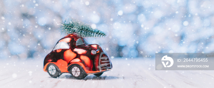 Close-up of a small toy car carries a xmas tree on the roof, concept Christmas and New Year