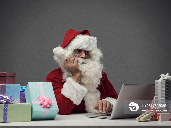 Disappointed Santa Claus connecting with his laptop