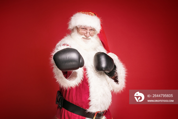 Real Santa Claus in boxing gloves on red background.