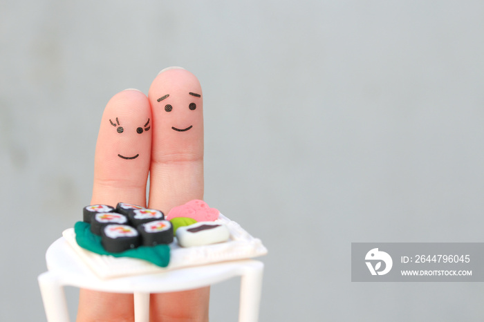 Fingers art of Happy couple. Man and woman eat sushi in cafe.