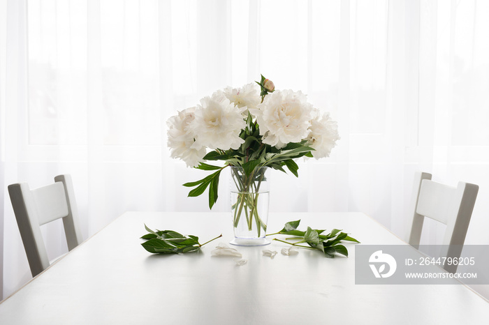 white peonies in a vase and fallen leaves on a white vintage table  - copy space