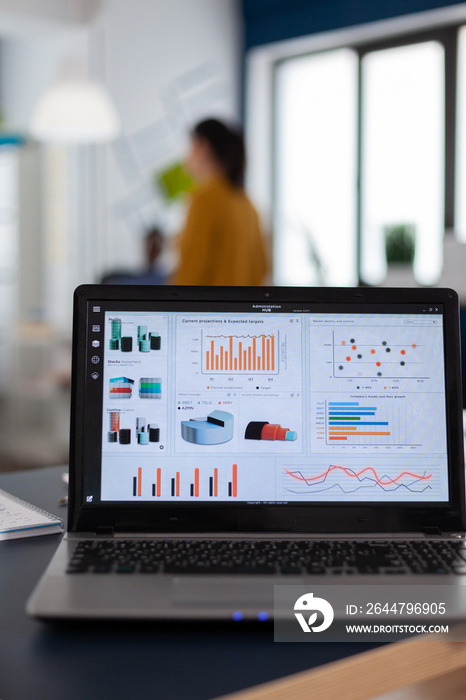 Laptop with marketing charts, graphs analitics in start up company. Workplace area in business cente