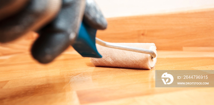 The painter  paints a varnish wooden board by roller