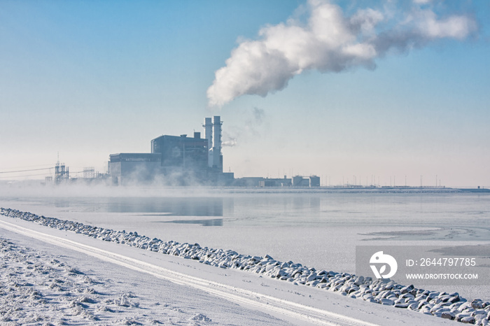 Dutch frozen lake covered with haze and view at a power plant