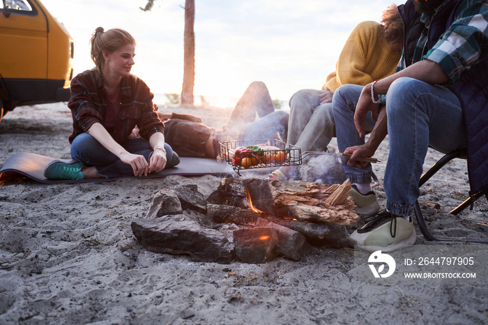 Friends sitting on the beach around campfire