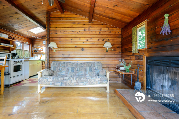 Cozy interior of a rustic log cabin with a kitchen and fireplace.