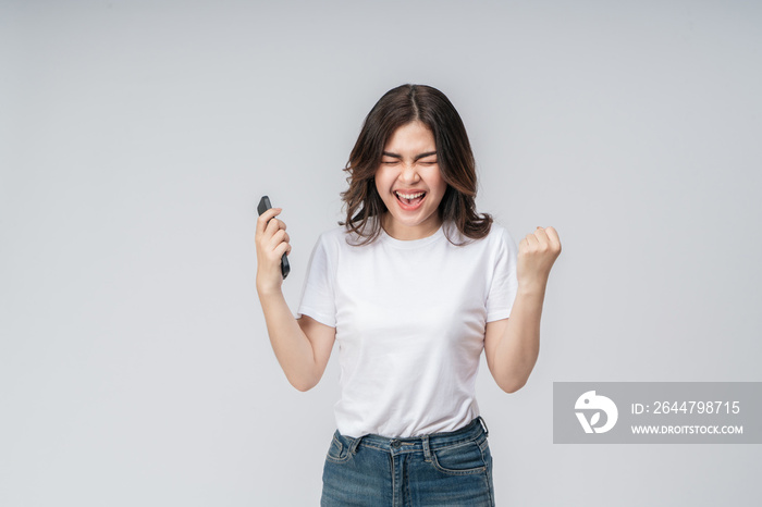 Expression on her face. Excited Asian woman in a white t-shirt holding a mobile phone feeling  happy