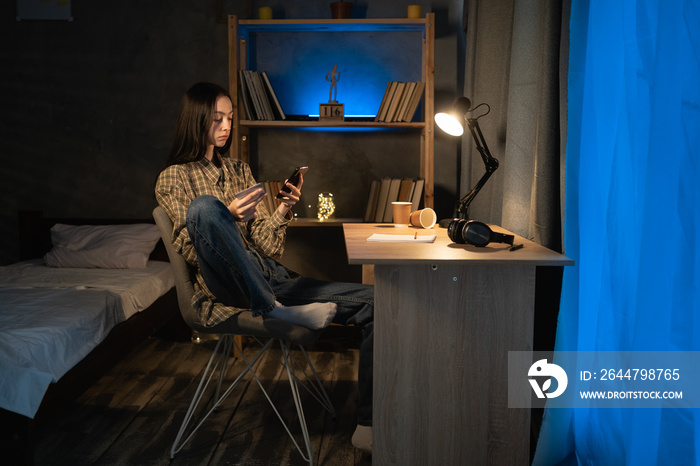 asian girl student hold a credit card and using a smart phone shopping online, sitting on table at h