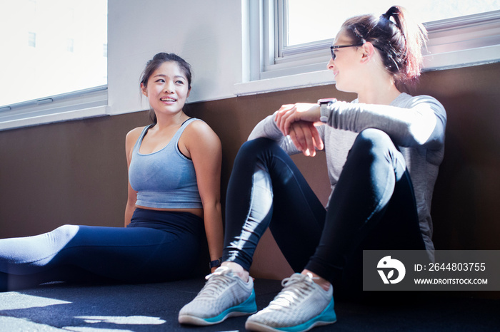 Female athletes talking while sitting on floor in gym