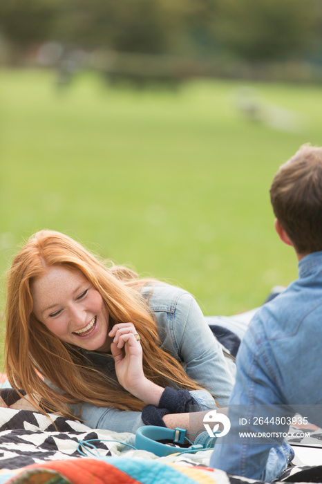 Happy young woman on blanket with boyfriend in park