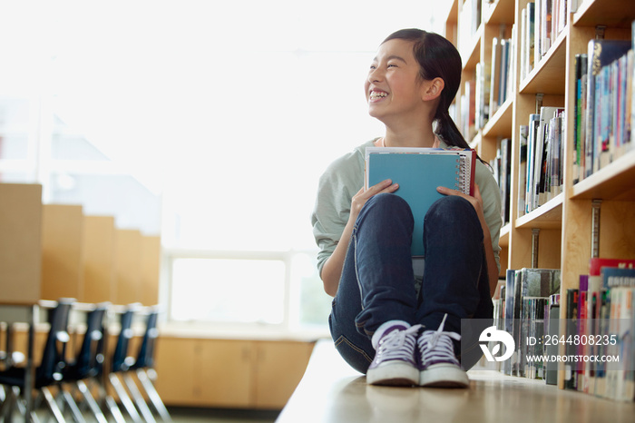 Asian, middle school student sitting on bench in library