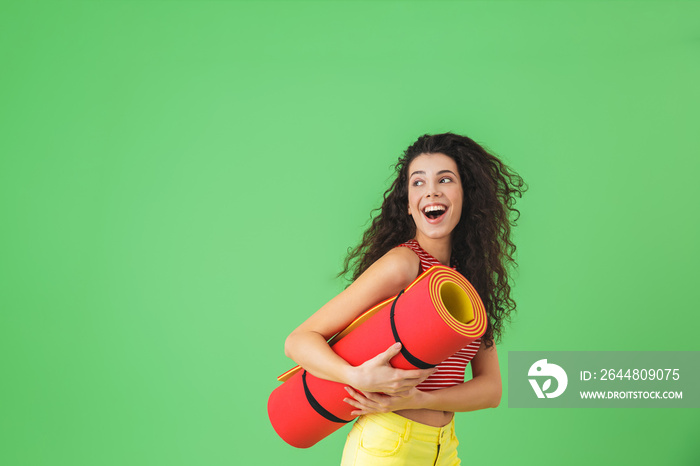 Photo of european woman 20s smiling and carrying yoga mat during workout