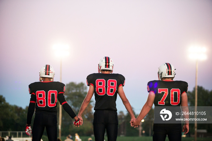 Rear view of American football players standing in field