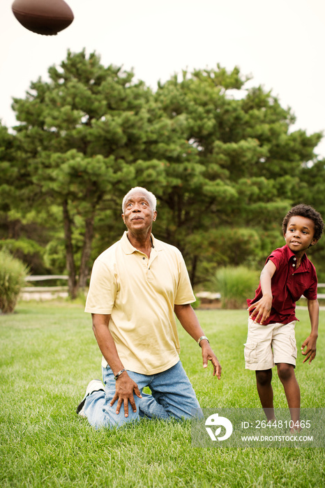 Boy with his grandfather throwing American football outdoors