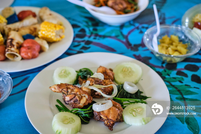 Traditional Fijian meal served on floor with tablecloth in traditional hut in village