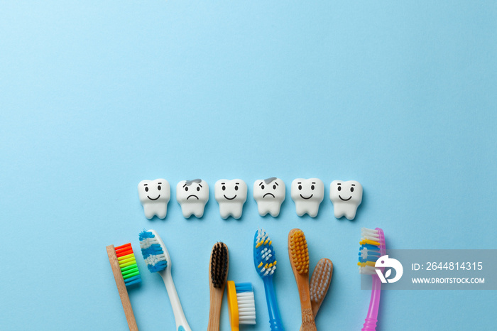 Healthy white teeth are smiling and tooth with caries is sad on blue background and Toothbrush. Copy