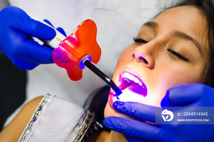 Close-up portrait of a female patient visiting dentist for teeth whitening in clinic