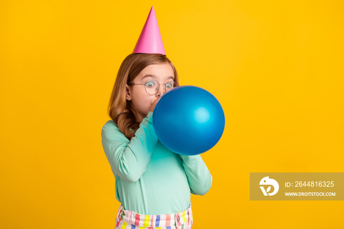 年轻小女孩吹气球装饰的侧面照片准备派对被黄色隔离