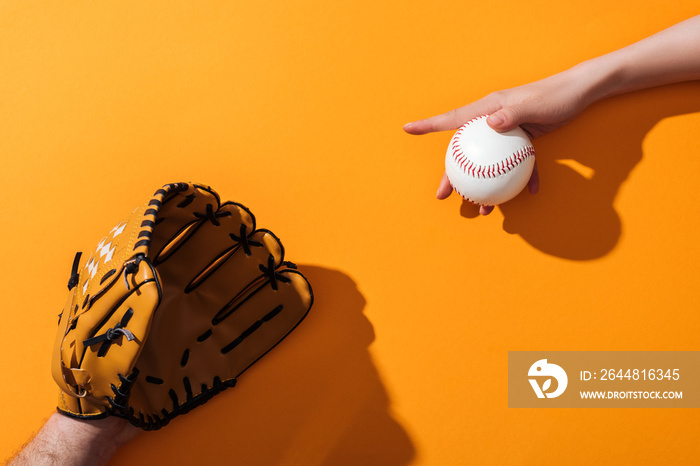 cropped view of man in brown baseball glove near woman holding softball on yellow