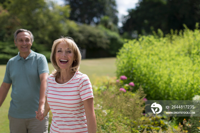 Portrait happy senior couple holding hands in sunny garden