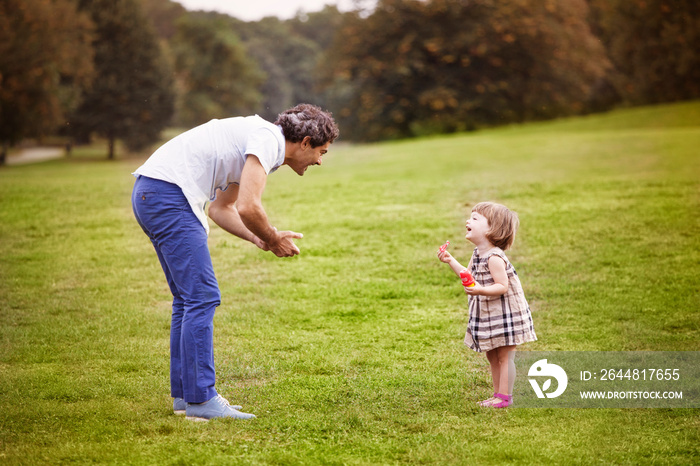 Side view of father playing with his daughter in Prospect Park