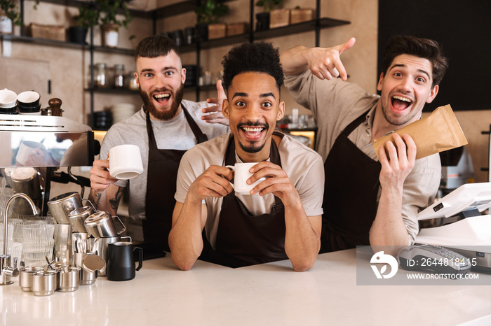 Group of cheerful men baristas wearing aprons