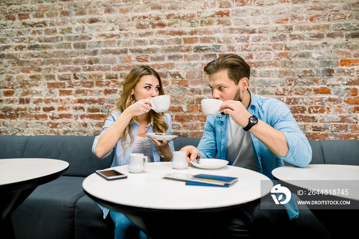 Happy young couple with passports and tickets, sitting at the table and drinking coffee, before the 