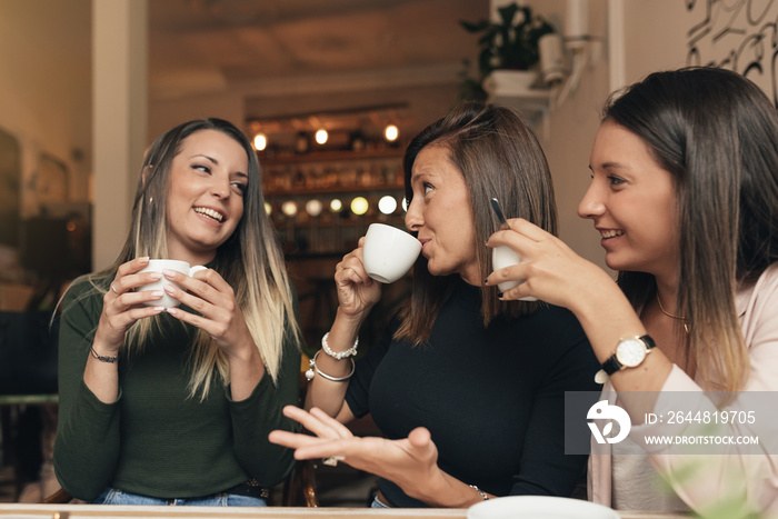 Three beautiful women drinking coffee and chatting.