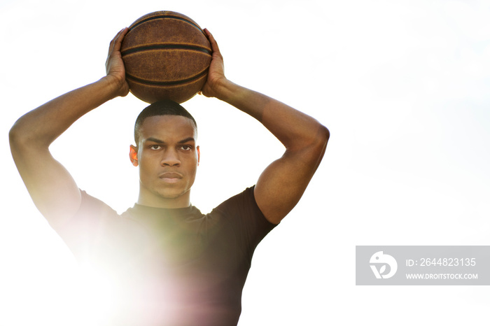 Young man holding basketball over head