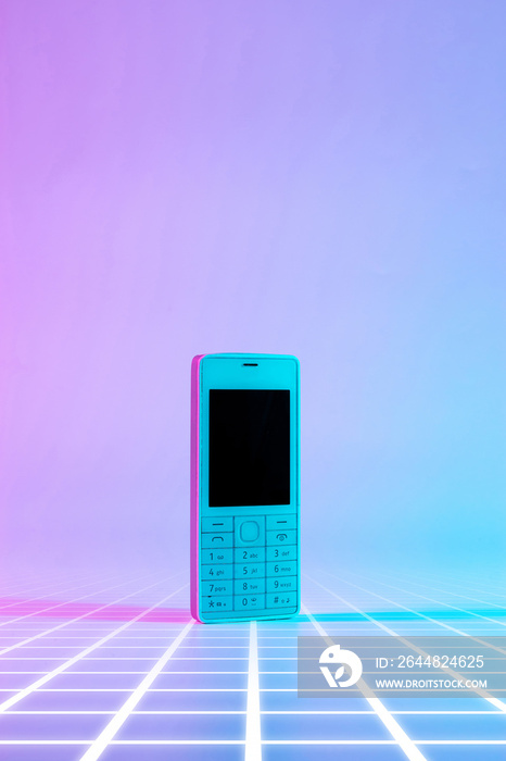 复古手机复古概念。霓虹粉蓝色灯光下的白色老式手机。复古波浪。Po