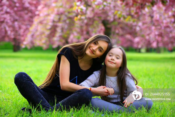 Happy beautiful young woman with girl in blossom park with trees and flowers.