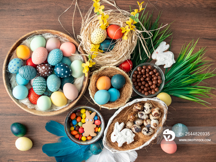五颜六色的复活节彩蛋在巢里，羽毛和木桌上的春花。复活节节日装饰