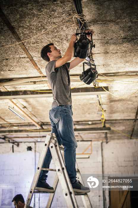 Behind the scene Lighting technician electric engineer adjusting stage lights. Spotlights in the the