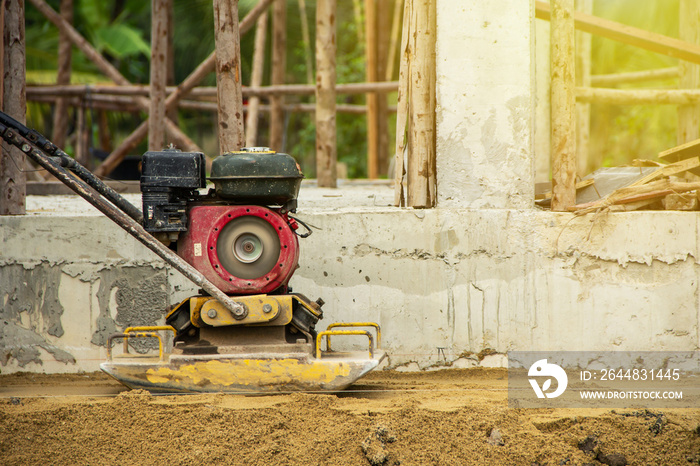 worker at sand ground compaction with vibration plate compactor machine. with a background is the st