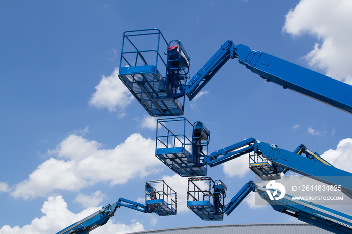 blue cherry picker over the metal factory roof against blue sky. Lift buckets machine.