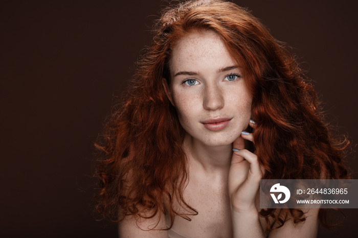 tender attractive redhead woman posing for studio shot, isolated on brown with copy space