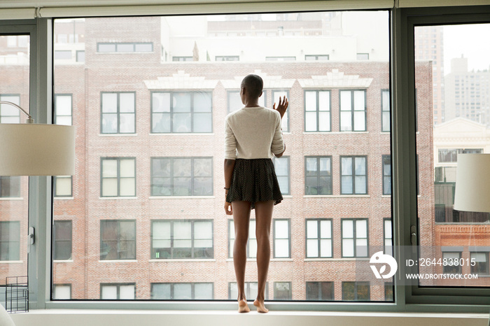 Rear view of woman looking through window at home