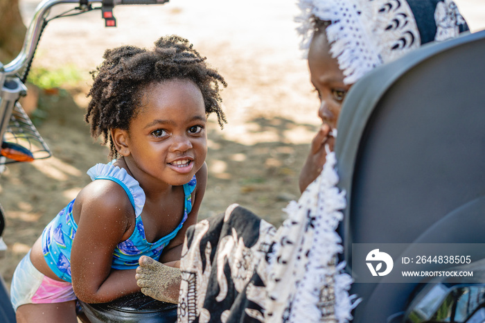 Imagen horizontal de una niña afroamericana junto a su pequeño hermano al aire libre en un hermoso d