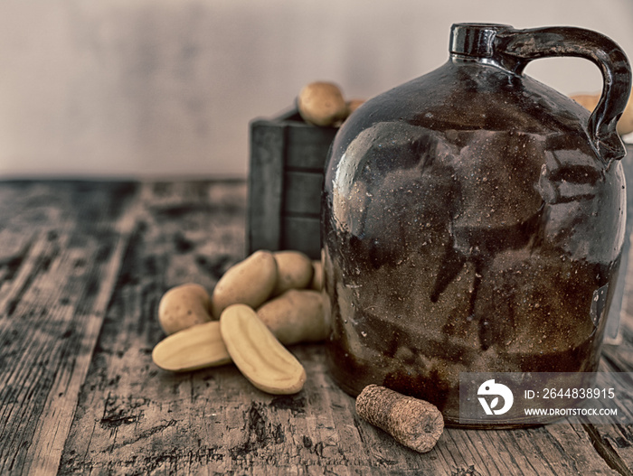 vintage moonshine jug on a rustic wooden table with potatoes and corn cob cork