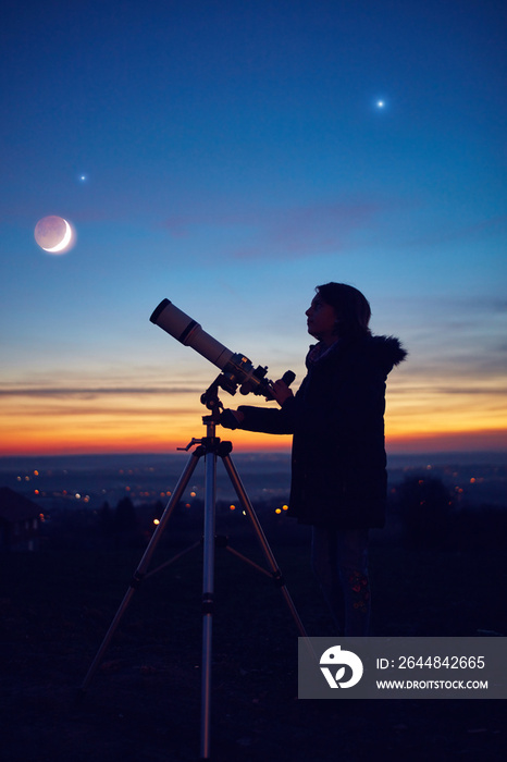 小女孩用天文望远镜观测恒星、行星、月亮和夜空。
