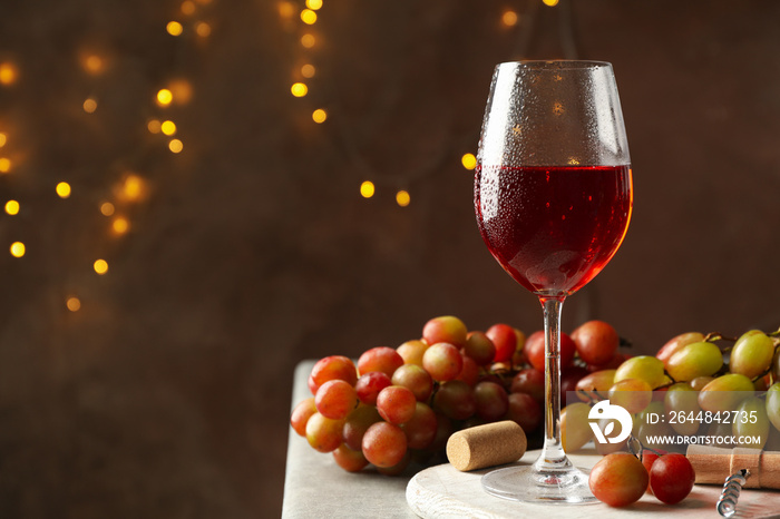 Composition with glass of wine and grape on brown background with blurred lights